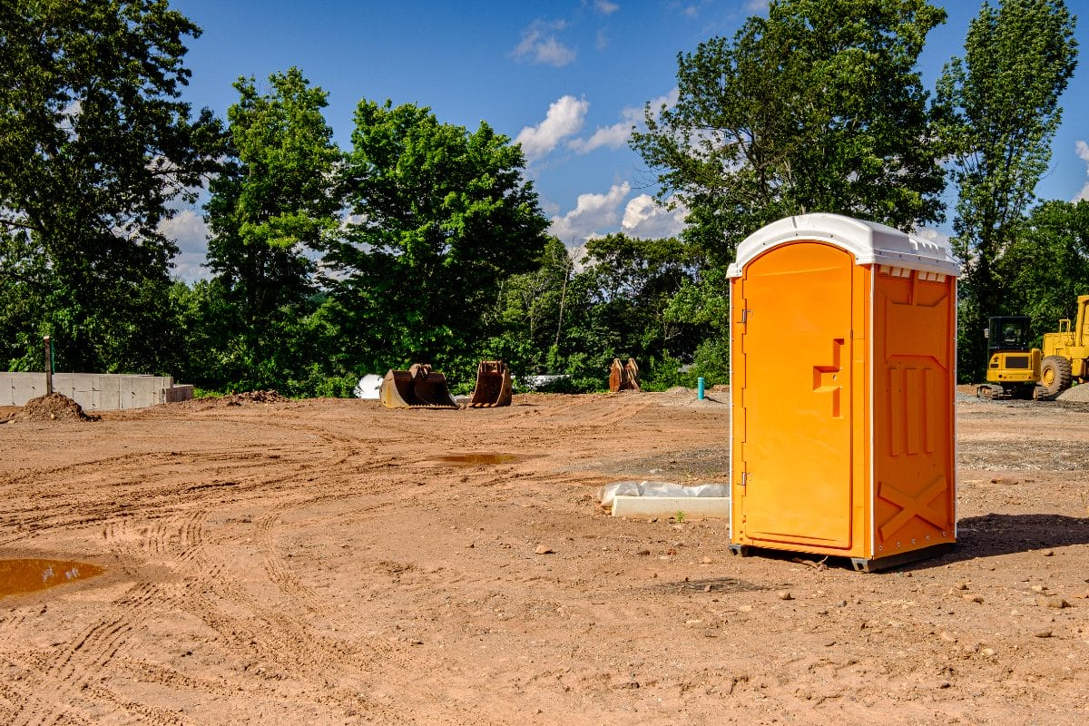 An orange porta-potty on a construction site