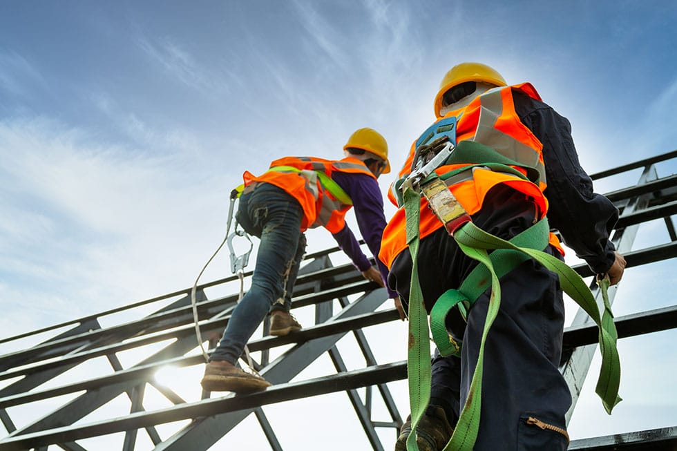 Workers with hard hats, using personal fall arrest systems at a construction site