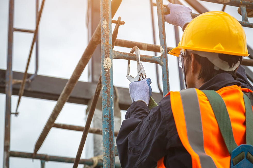 worker attaching harness to scaffolding following safety regulations