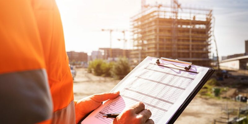 construction site manager reviewing OSHA standards checklist